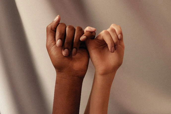 two hands with linked pinky fingers